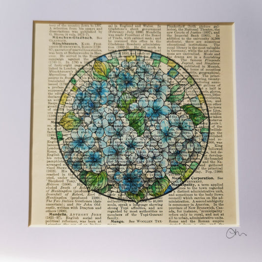 A framed art piece featuring a watercolour and ink illustration of blue hydrangea flowers on a vintage book page, displayed in a white card mount