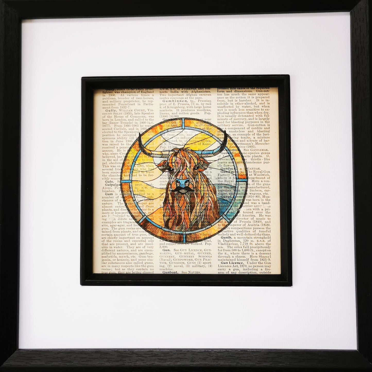 Close up of framed artwork featuring a watercolour and ink illustration of a Highland Cow on a vintage encyclopaedia page.