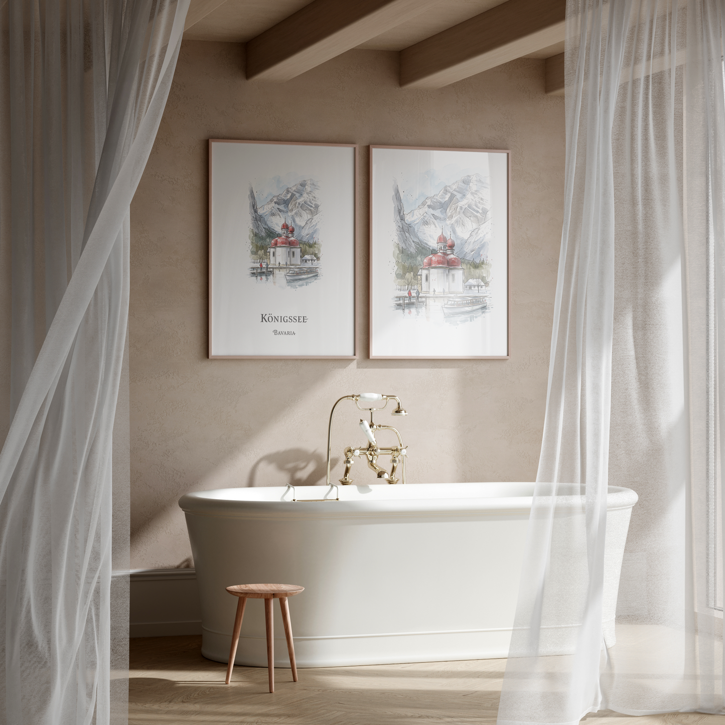 A styled bathroom scene with two framed watercolour landscape prints hanging above a white freestanding bathtub. The prints depict mountain scenery with small buildings and the text 'Königssee' and 'Austria.