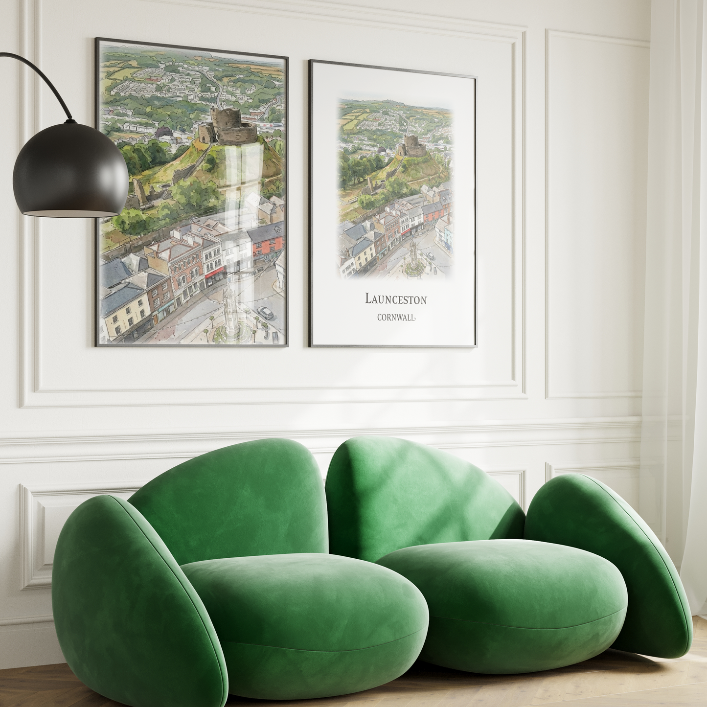 2 art prints of Launceston castle and Town Centre seen from above, displayed on a white wall with quirky green sofa in front and arched floor light.