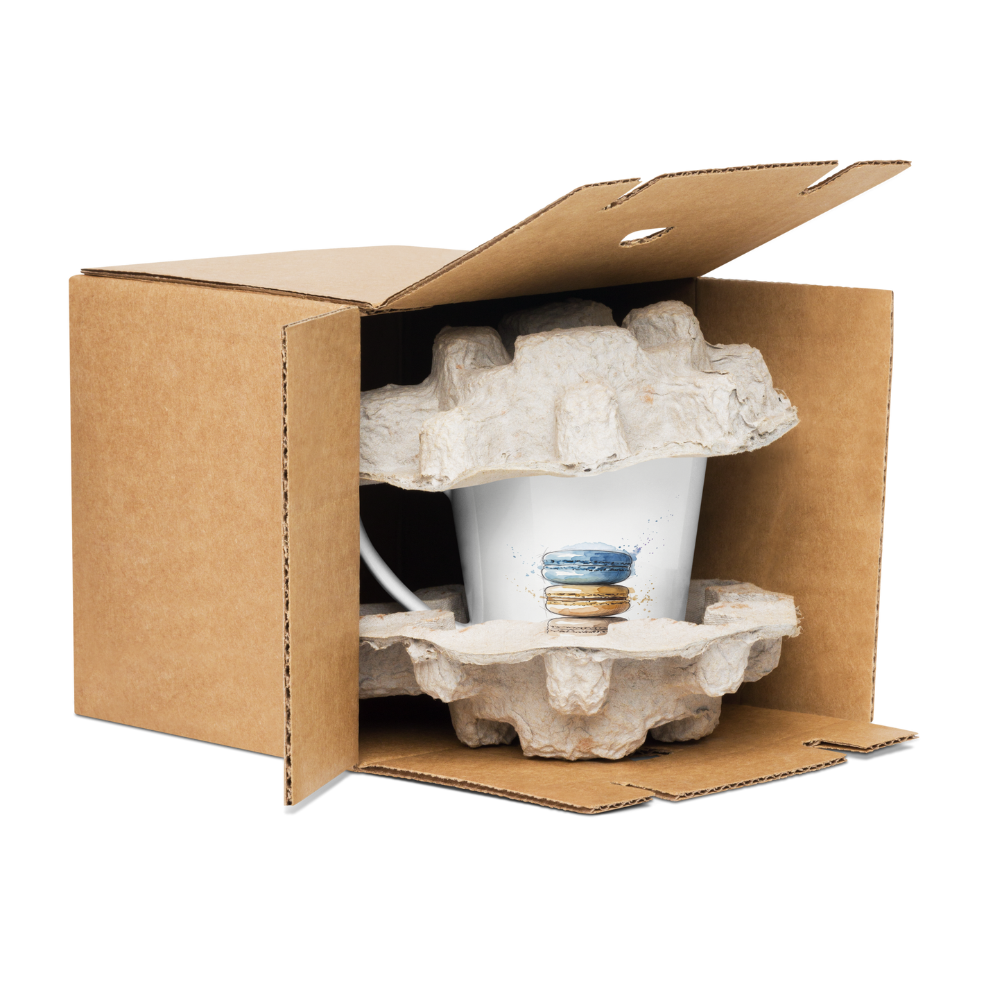 A white ceramic mug with a blue and orange watercolour print of a stack of macarons, nestled inside a brown cardboard box with protective foam inserts, isolated on a white background.