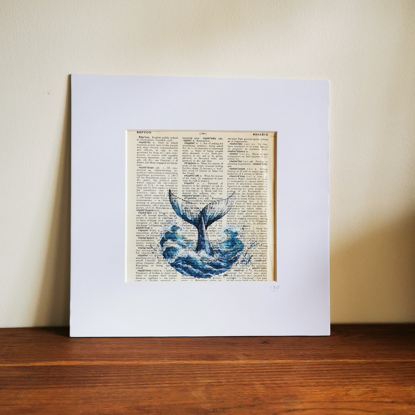 Framed artwork of a whale tail on a printed page with a white border.