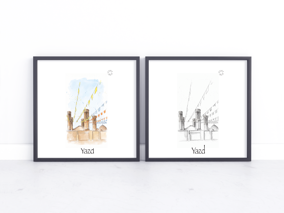 Two framed art prints leaning against a white wall on a light marble surface. The left print shows a watercolour-style cityscape with colourful flags and the word 'Yazd' at the bottom, and the right print shows a black-and-white sketch of the same cityscape with the word 'Yazd'.
