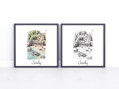 Two framed art prints leaning against a white wall on a light marble surface. The left print is a watercolour-style coastal scene with green trees and blue water, labeled 'Clovelly' at the bottom.