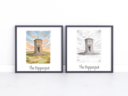Two framed art prints leaning against a white wall on a light surface. The left print is a watercolour illustration of a stone tower labeled 'The Pepperpot' with a colourful sky, and the right print is a black-and-white sketch of the same tower labeled 'The Pepperpot'.