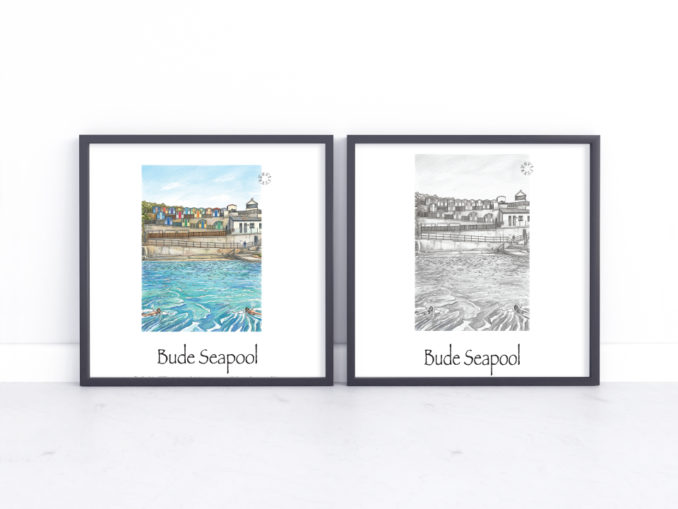 Two framed art prints of Bude Seapool, one in a watercolour style with colourful beach huts and blue water, and one in a black and white sketch style, displayed side-by-side on a white marble surface against a white wall.