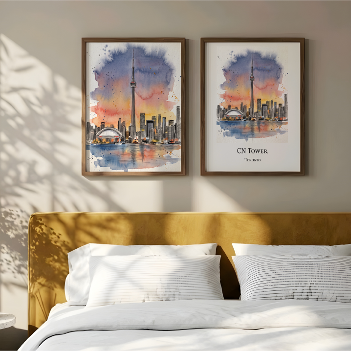 Two framed watercolour prints of the CN Tower in Toronto displayed above a bed in a modern bedroom setting with warm sunlight and leaf shadows.