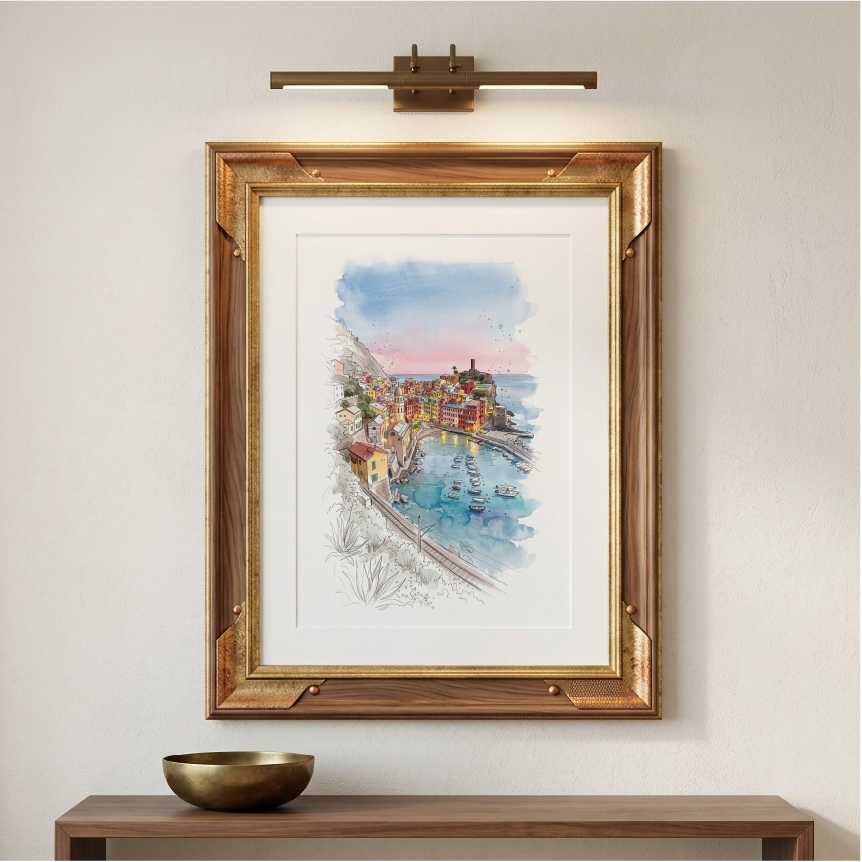 Framed watercolour art print of Cinque Terre displayed on a wall above a wooden console table with a decorative bowl. The print features a colourful seaside town by the sea, with blue water and sky, and is housed in a gold-toned wooden frame with a white mount.