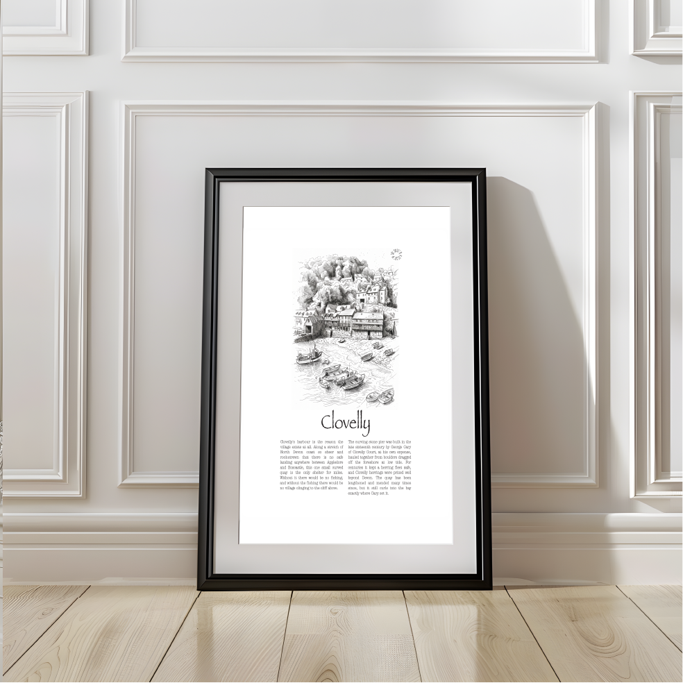 A framed black-and-white art print titled 'Clovelly' leaning against a white paneled wall on a light wood floor.