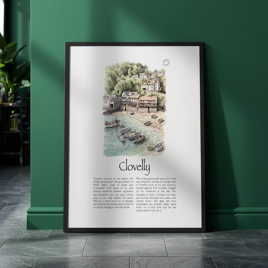 A framed art print titled 'Clovelly' leaning against a dark green wall on a dark tiled floor. The print features a detailed watercolour illustration of a coastal village with boats on the sea, above printed text.