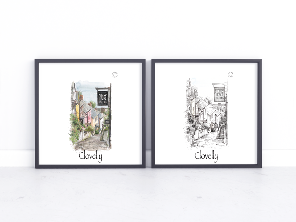 Two framed art prints leaning against a white wall on a light surface. The left print is a colourful watercolour illustration of a street scene with the word 'Clovelly' below, and the right print is a black-and-white sketch of the same street scene with 'Clovelly' below.