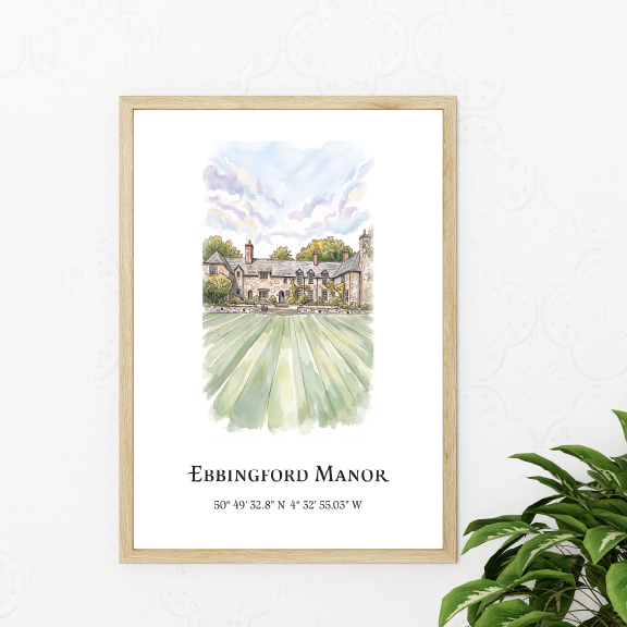 A framed watercolour art print of Ebbingford Manor with coordinates and latitude/longitude details, styled on a white wall next to a green houseplant.