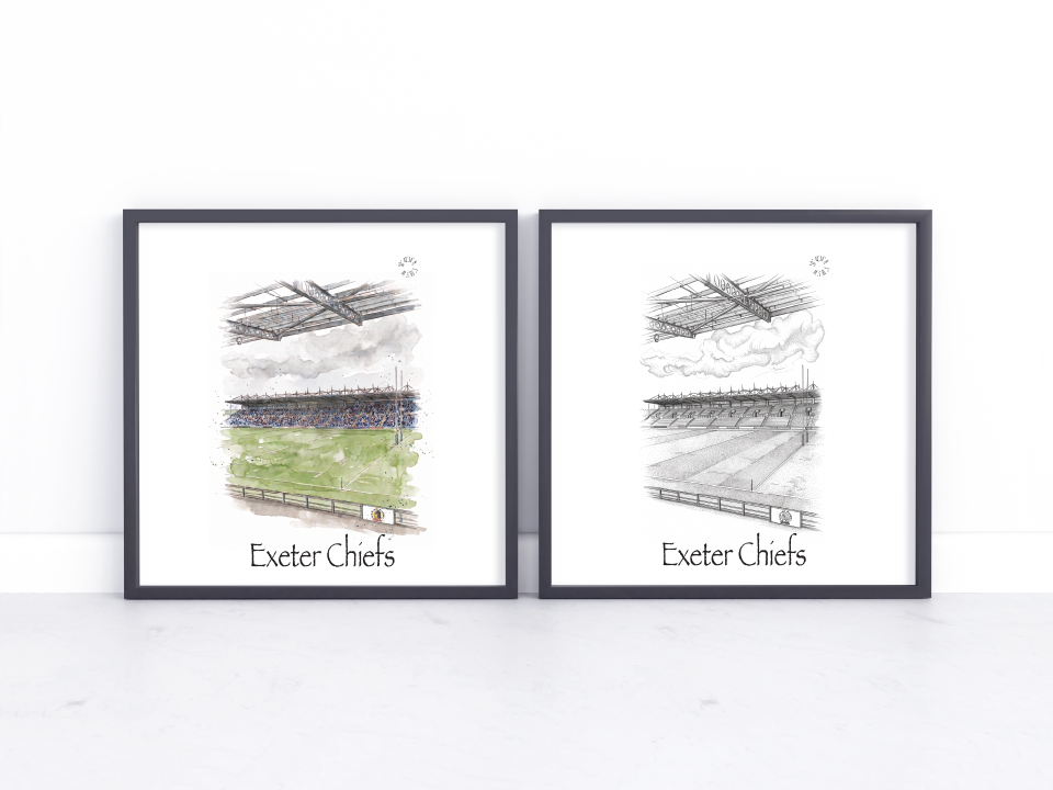 Two framed art prints leaning against a white wall on a light surface. Each print shows a sketch of an Exeter Chiefs stadium scene with one print in watercolour and the other in black and white.