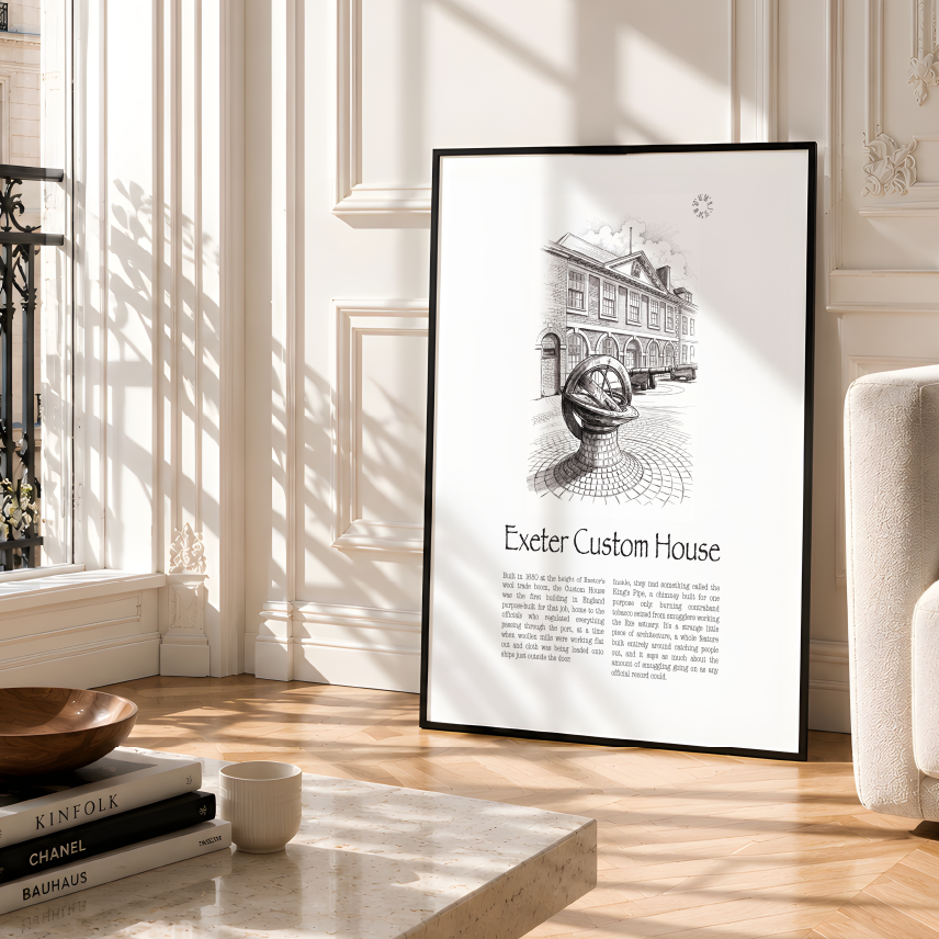 A framed black-and-white art print leaning against a cream-coloured wall in a bright, modern living room with a marble coffee table and a beige armchair.