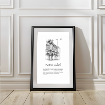 A framed black and white architectural art print of Exeter Guildhall, leaning against a white paneled wall on a light wood floor.