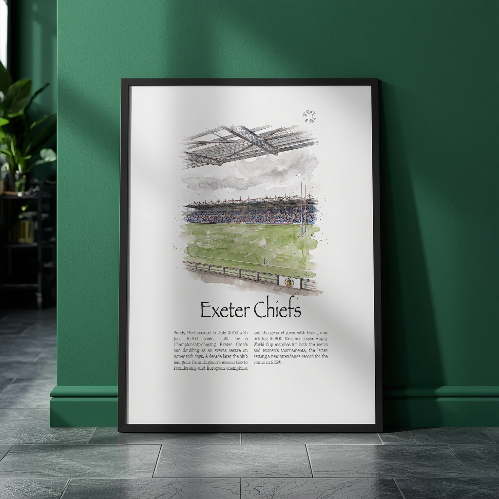 A framed vertical art print featuring a watercolour illustration of Exeter Chiefs rugby stadium and team text, leaning against a dark green wall on a dark tiled floor.