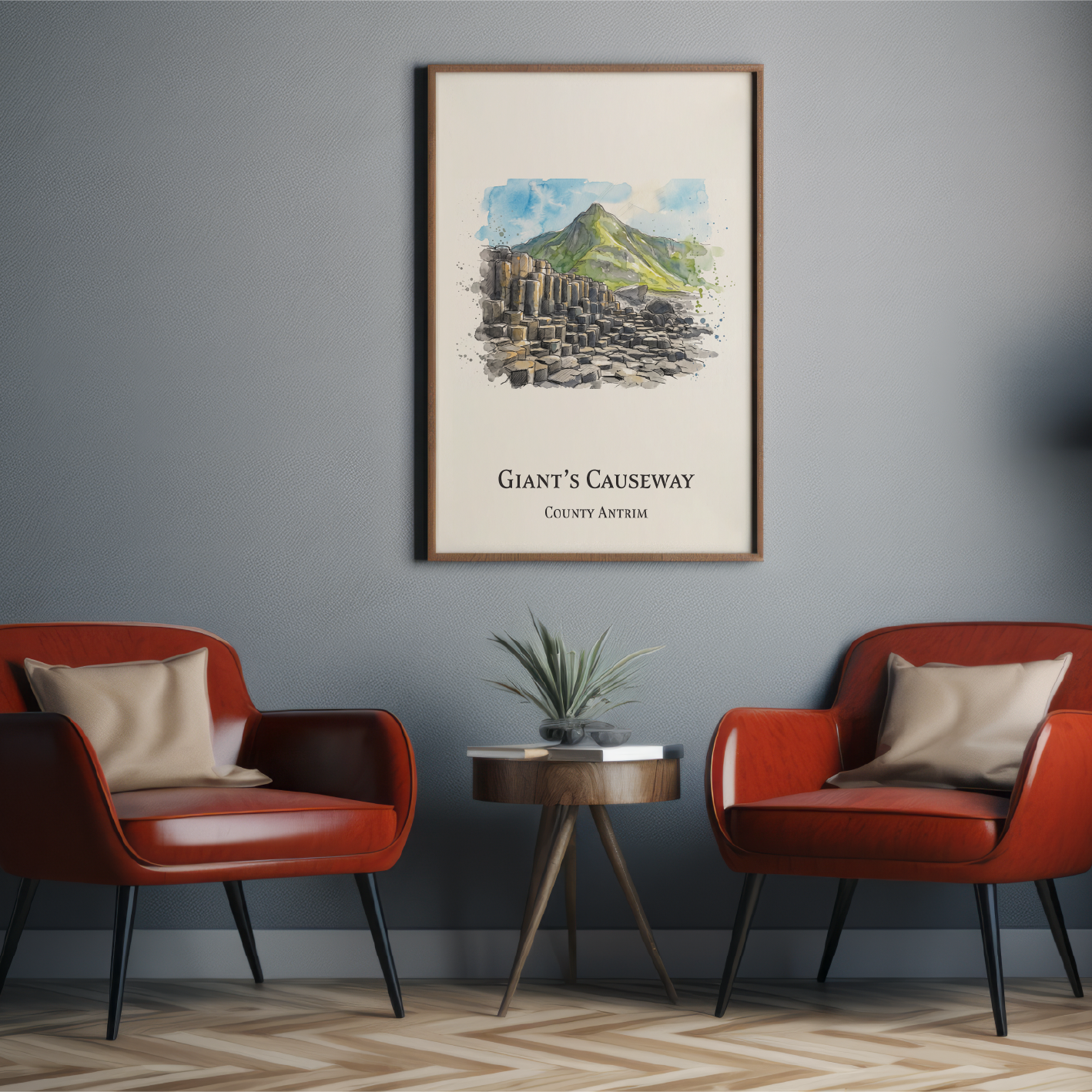 A framed art print titled 'Giant's Causeway' hangs on a dark gray wall in a modern living room setting with two red armchairs, a small side table, and a floor lamp.