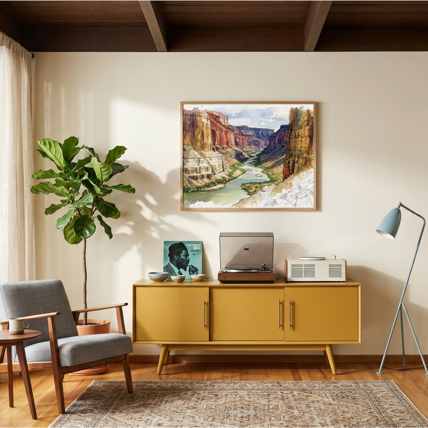 A framed landscape painting of the Grand Canyon hangs on a beige wall in a styled living room with a mustard yellow sideboard, a gray armchair, a potted fiddle-leaf fig, and a floor lamp.