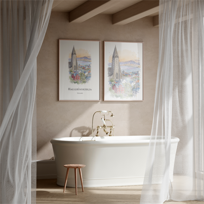 A styled bathroom scene with a white freestanding bathtub, gold faucet, sheer white curtains, and two framed vertical art prints hanging on the beige wall above the tub. The prints depict a church spire and a coastal city scene with the text 'HALLGRËUSKERJUN' and 'Iceland'.