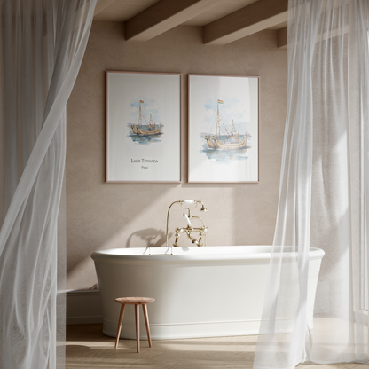 Two framed nautical art prints depicting sailboats on water, labeled 'LAKE TITICACA Peru', hanging on a beige wall above a white freestanding bathtub in a softly lit bathroom with sheer white curtains.