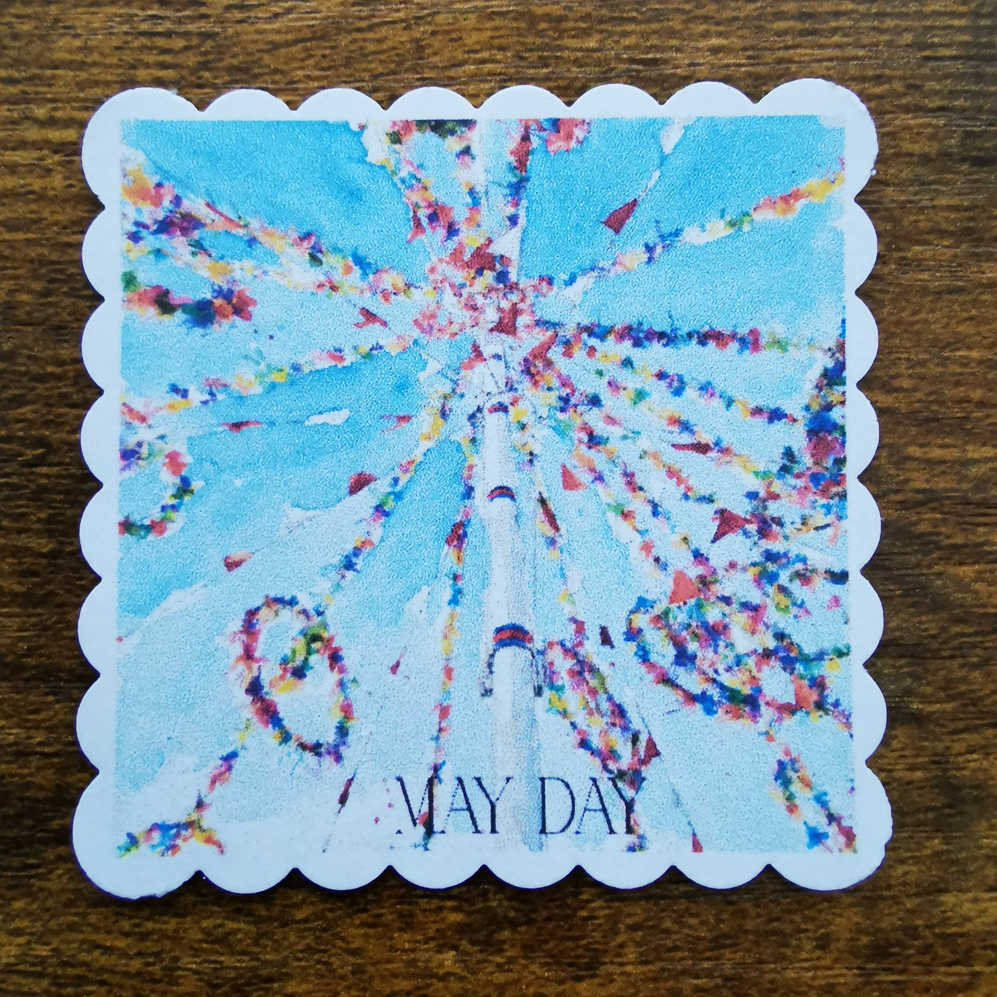 Maypole illustration faux stamp with 'May Day' text on a wooden surface
