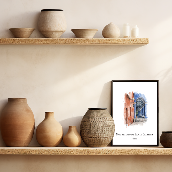 A framed art print of Monasterio de Santa Catalina, Peru styled on a rustic wooden shelf alongside terracotta and ceramic vases against a warm beige wall.