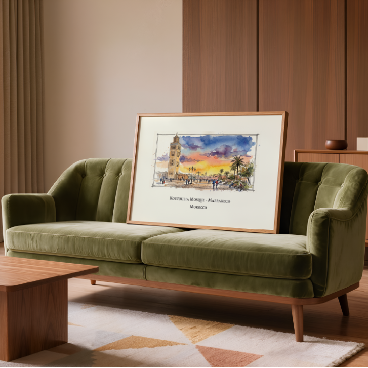 A framed art print depicting a colourful sunset over the historic Marrakech square in Morocco styled on a green velvet sofa in a modern, warm-toned living room.