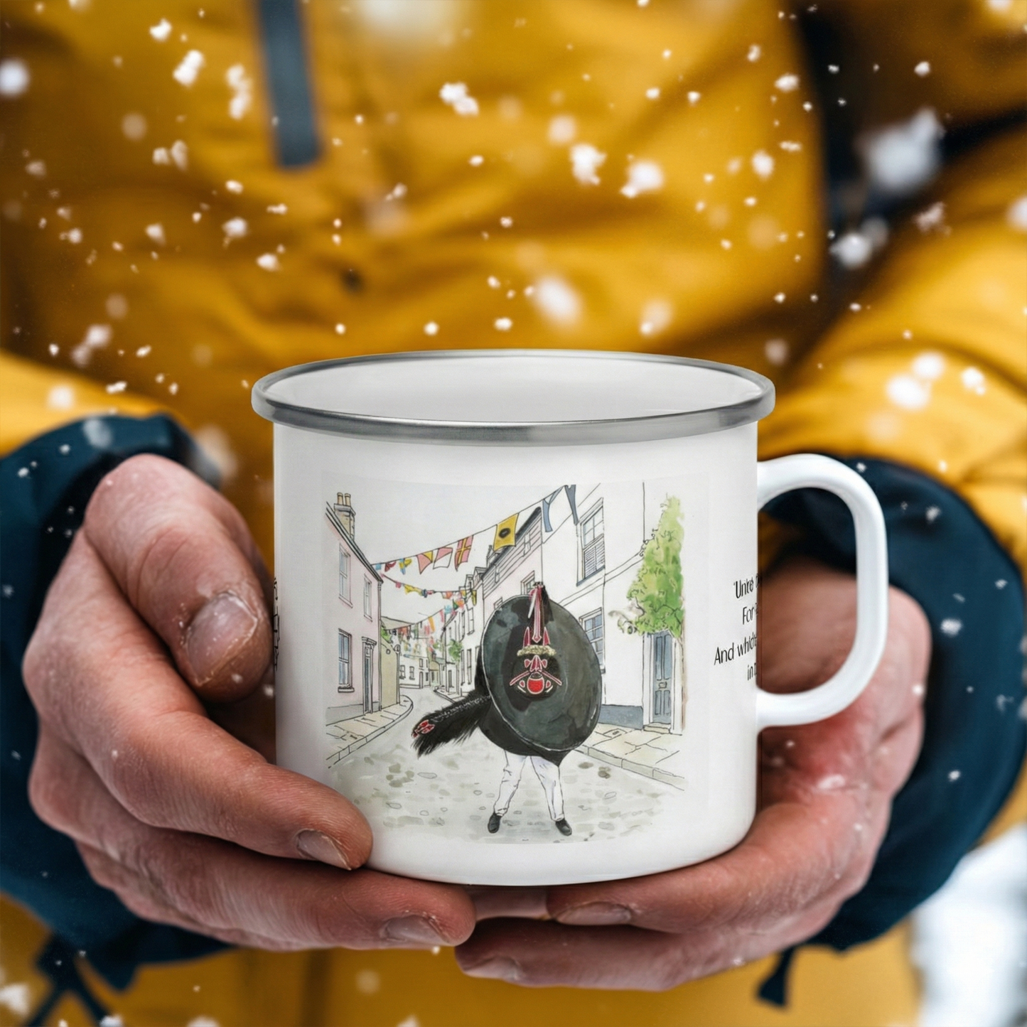 Person holding a mug with a design of a Red Obby Oss and flags in a snowy setting