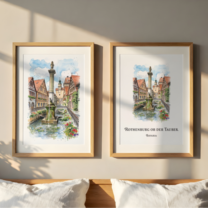 Two framed watercolour art prints of the Rothenburg or der Tauer fountain in Germany, displayed side-by-side on a beige wall above a wooden headboard with white pillows.
