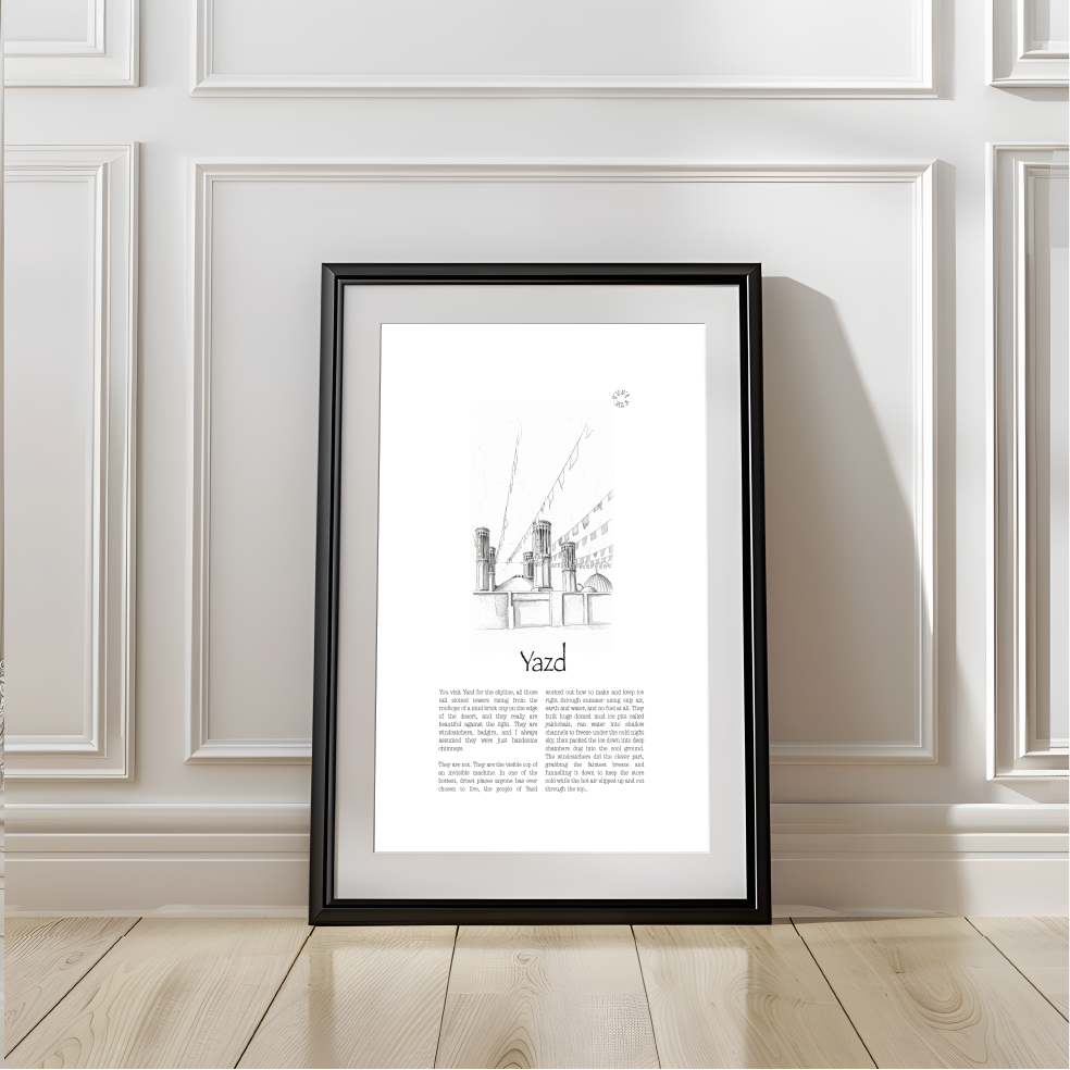 A framed black and white architectural art print of Yazd Rooftops, leaning against a white paneled wall on a light wood floor.