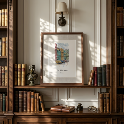 A framed art print featuring a colourful watercolor illustration of 'The Malecon' in Havana, styled on a wooden bookshelf with vintage books, a lamp, and a small bust in a warm, classic room setting.
